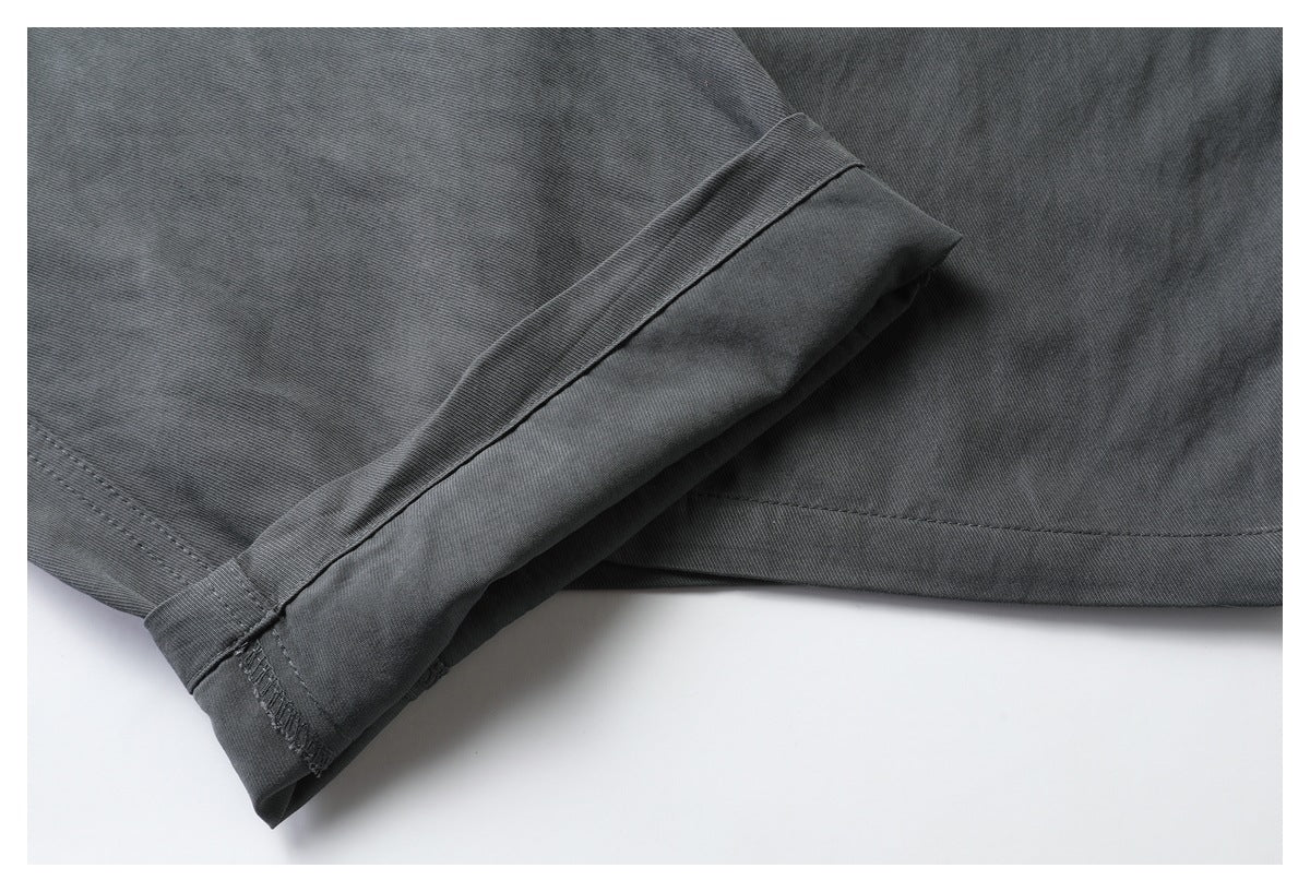 Close-up of a folded and stitched cuff or trouser hem in charcoal fabric.