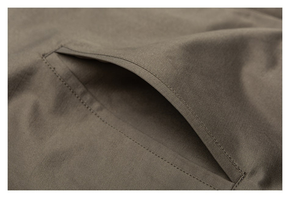 Close-up of a slanted welt pocket on taupe jacket fabric.