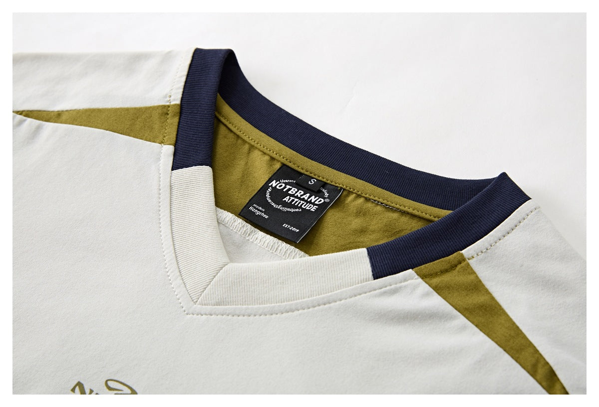 Close-up of an ivory T-shirt neckline with navy ribbing, olive panels, and a black sewn-in label.
