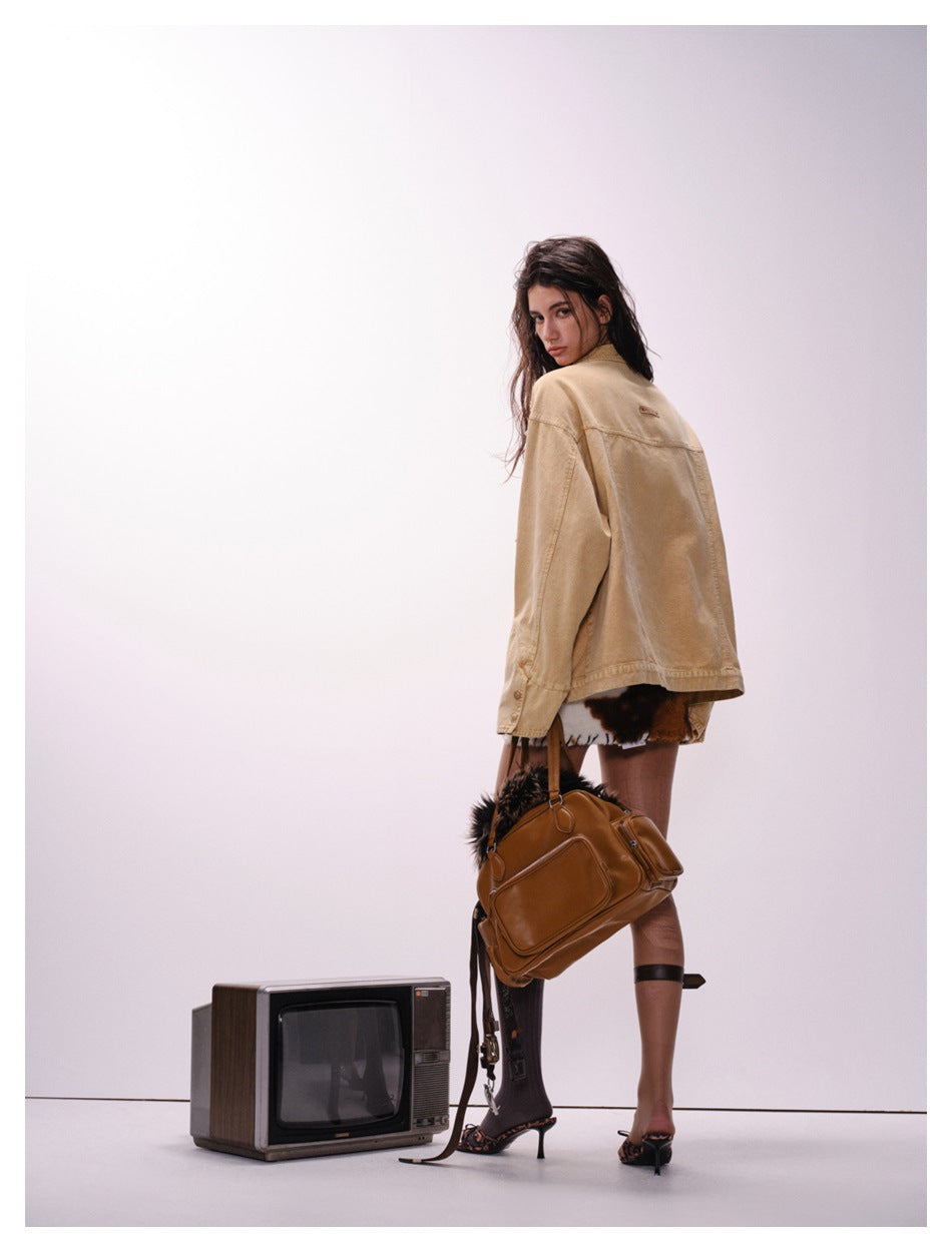 Model looking back while wearing the plain tan back of an oversized jacket.
