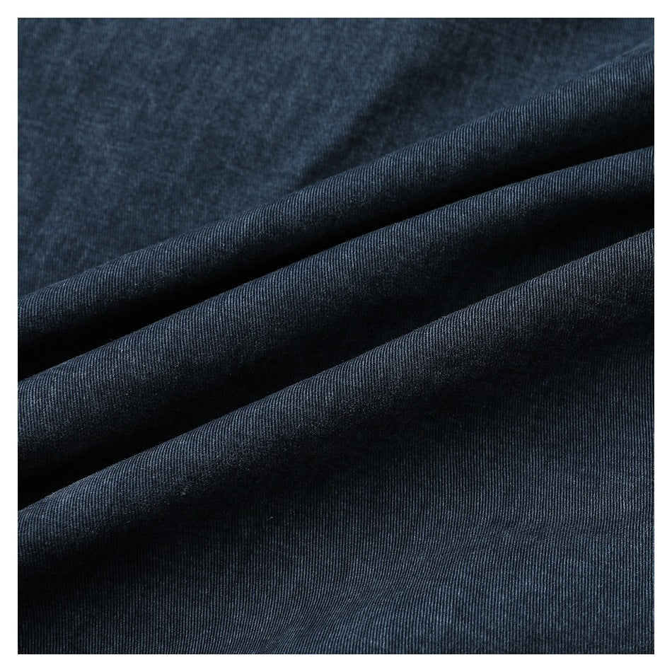 Close-up of dark blue denim fabric arranged in soft folds, showing its diagonal weave.
