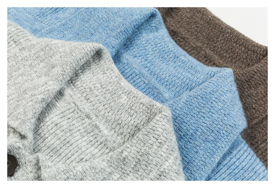 Close-up of overlapping gray, blue, and brown knit cardigans showing textured fabric and ribbed edges.