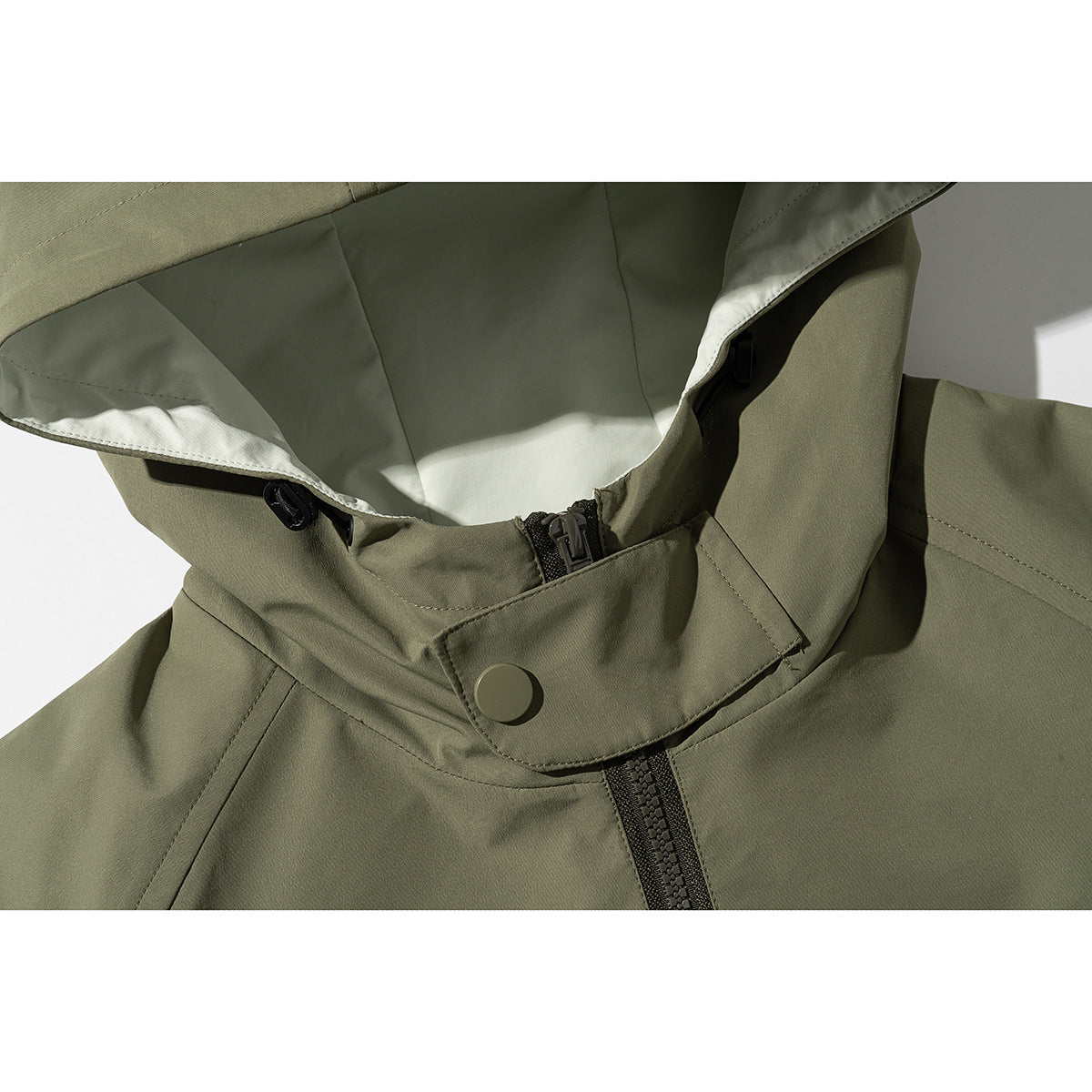Close-up of an olive hooded jacket showing the lined hood, snap-fastened collar, and front zipper.
