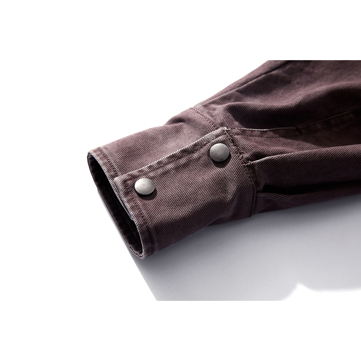 Close-up of a dark plum jacket sleeve cuff with two metal snap buttons.