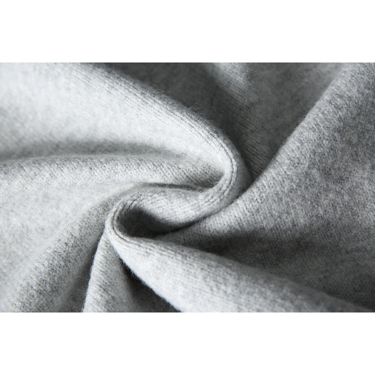 Macro view of light gray knit fabric folded to show its soft-looking texture and edge.