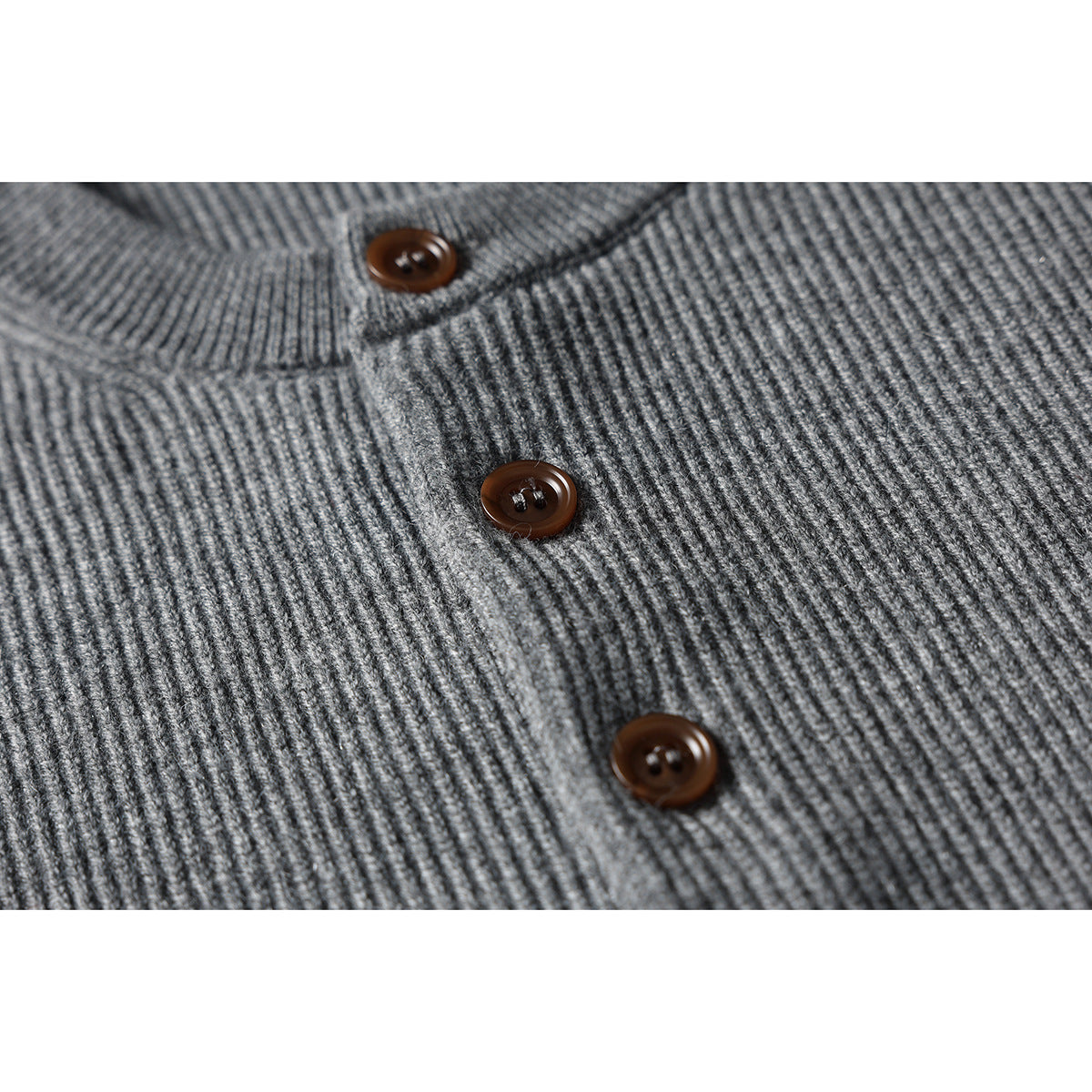 Close-up of a gray rib-knit sweater front with three brown buttons on its placket.