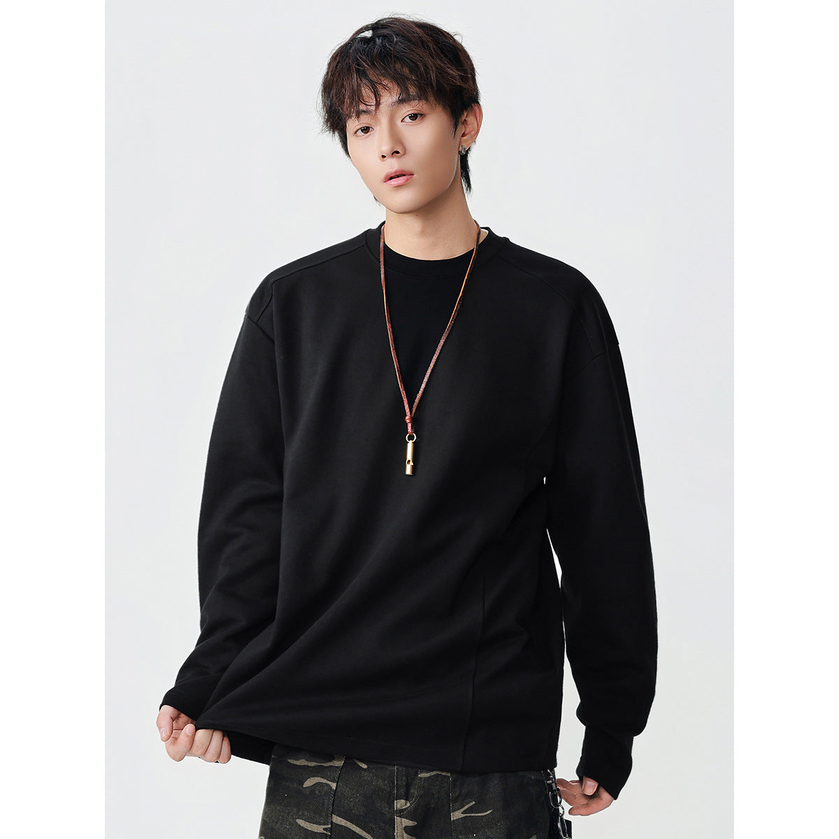 Model wearing an oversized black long-sleeve crewneck top with seamed shoulders.