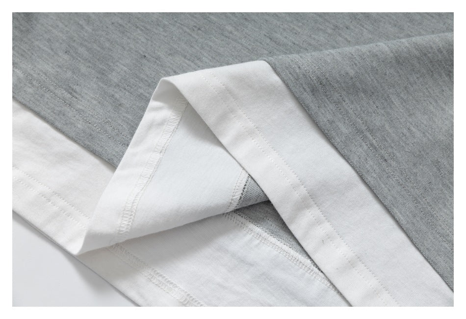 Close-up of a white garment hem folded back to reveal overlock stitching against gray fabric.