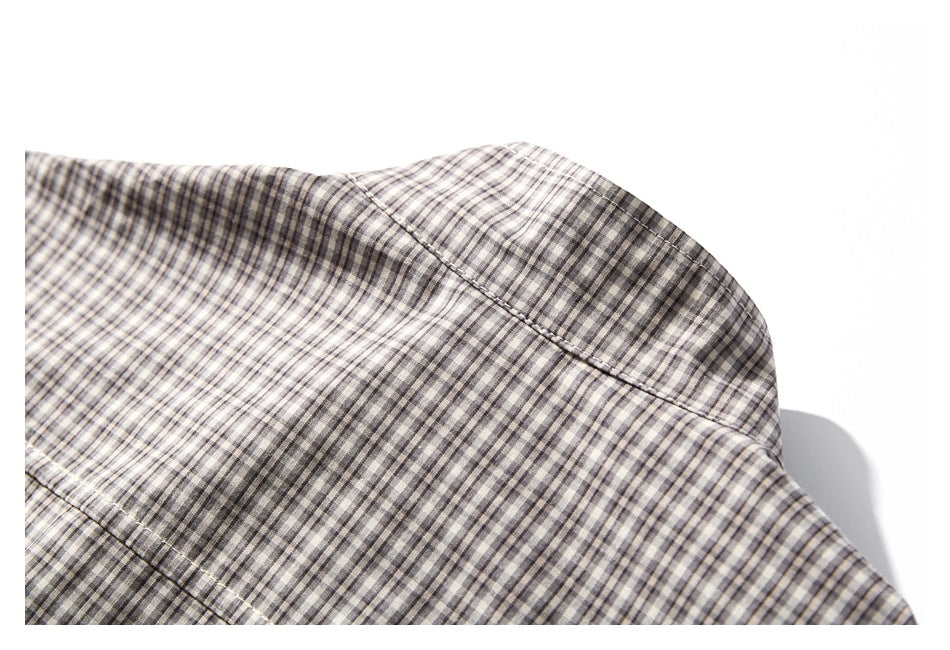 Close-up of a seam across the upper section of a gray and cream checked shirt.