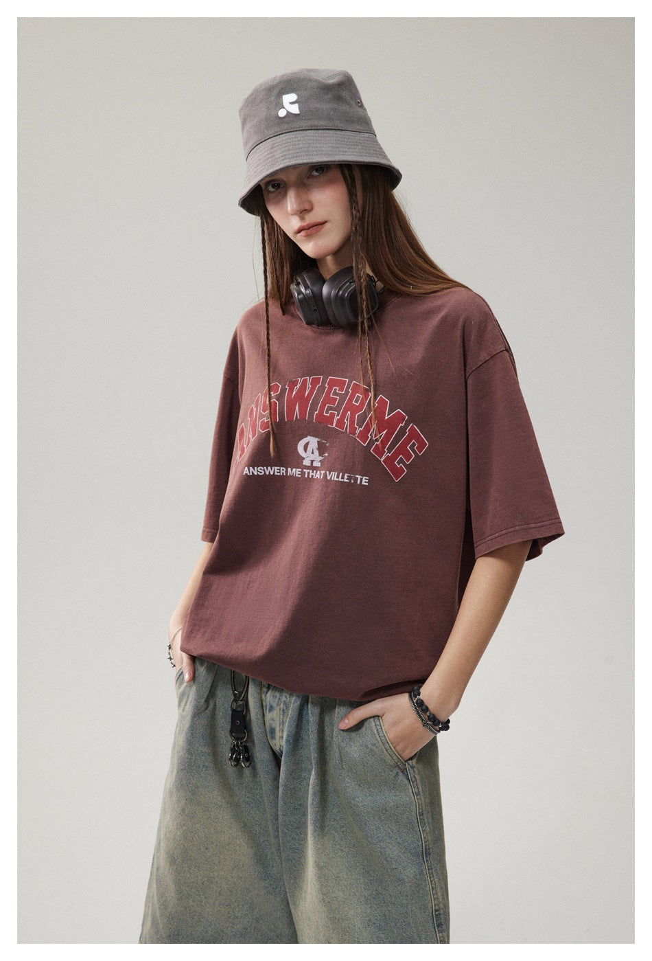 Model wearing a burgundy graphic T-shirt and gray bucket hat, shown from the waist up.