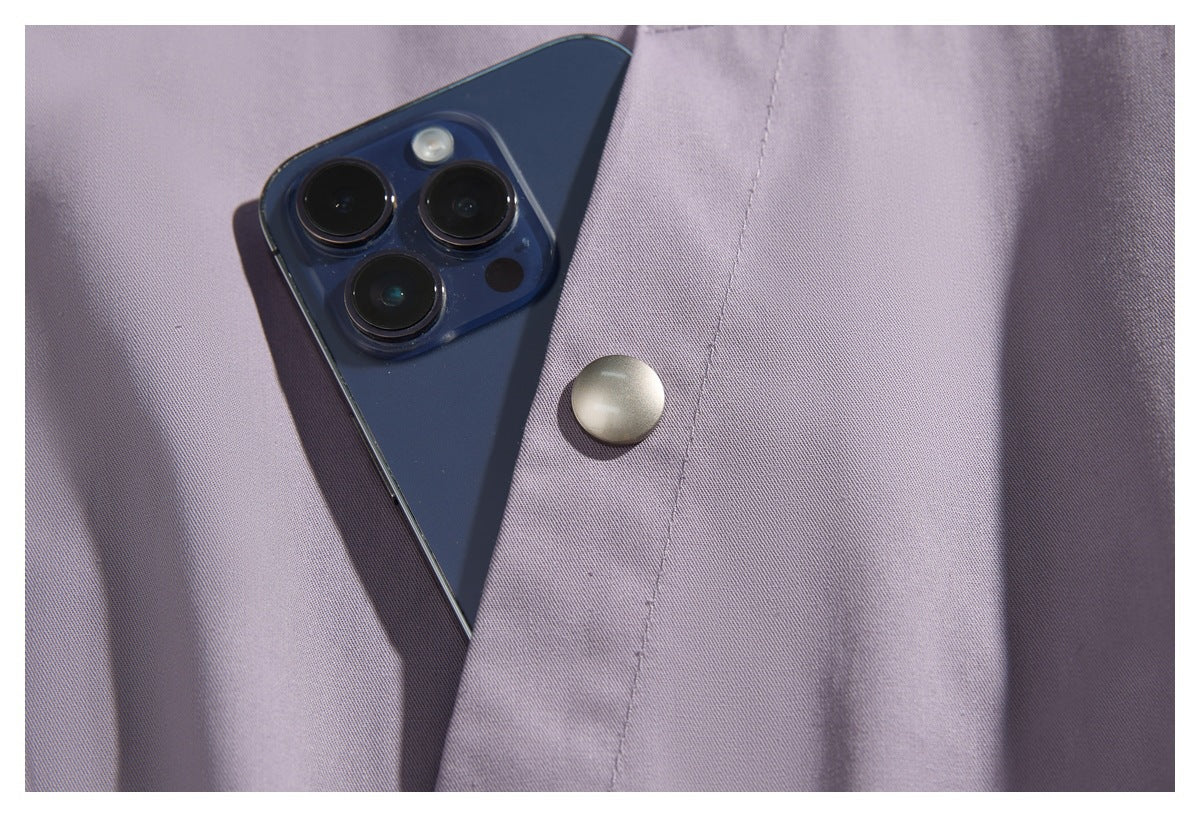 Close-up of a lavender jacket's snap-fastened pocket with a phone tucked inside.