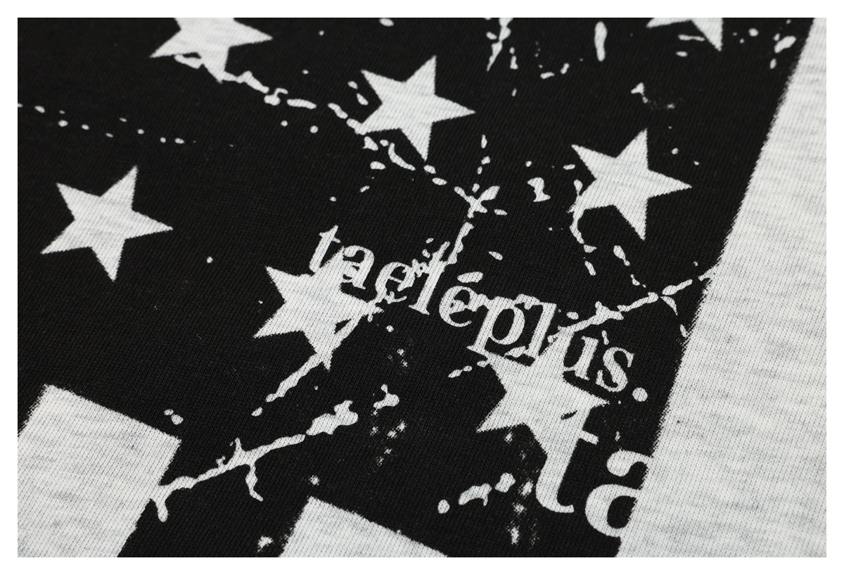 Close-up of white lettering and stars within a distressed black print on light gray T-shirt fabric.