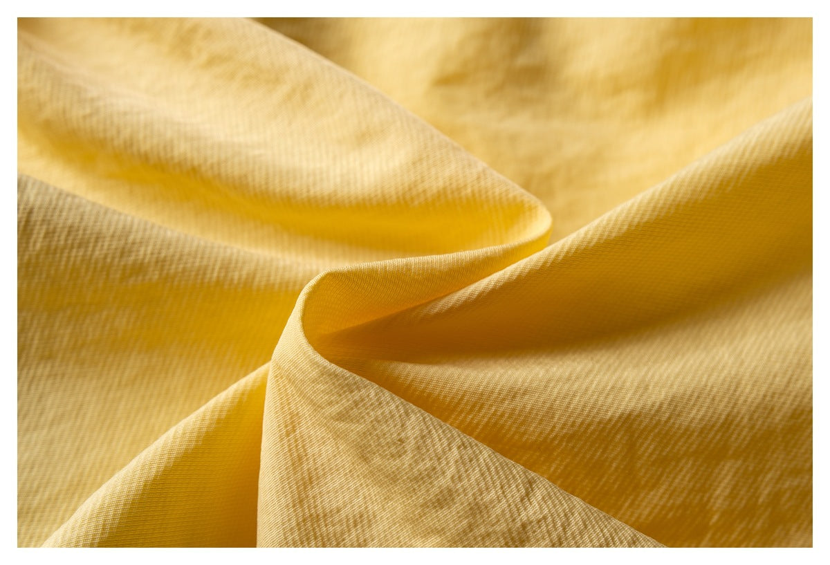 Macro view of pale yellow fabric folded to show its fine woven texture and pattern.