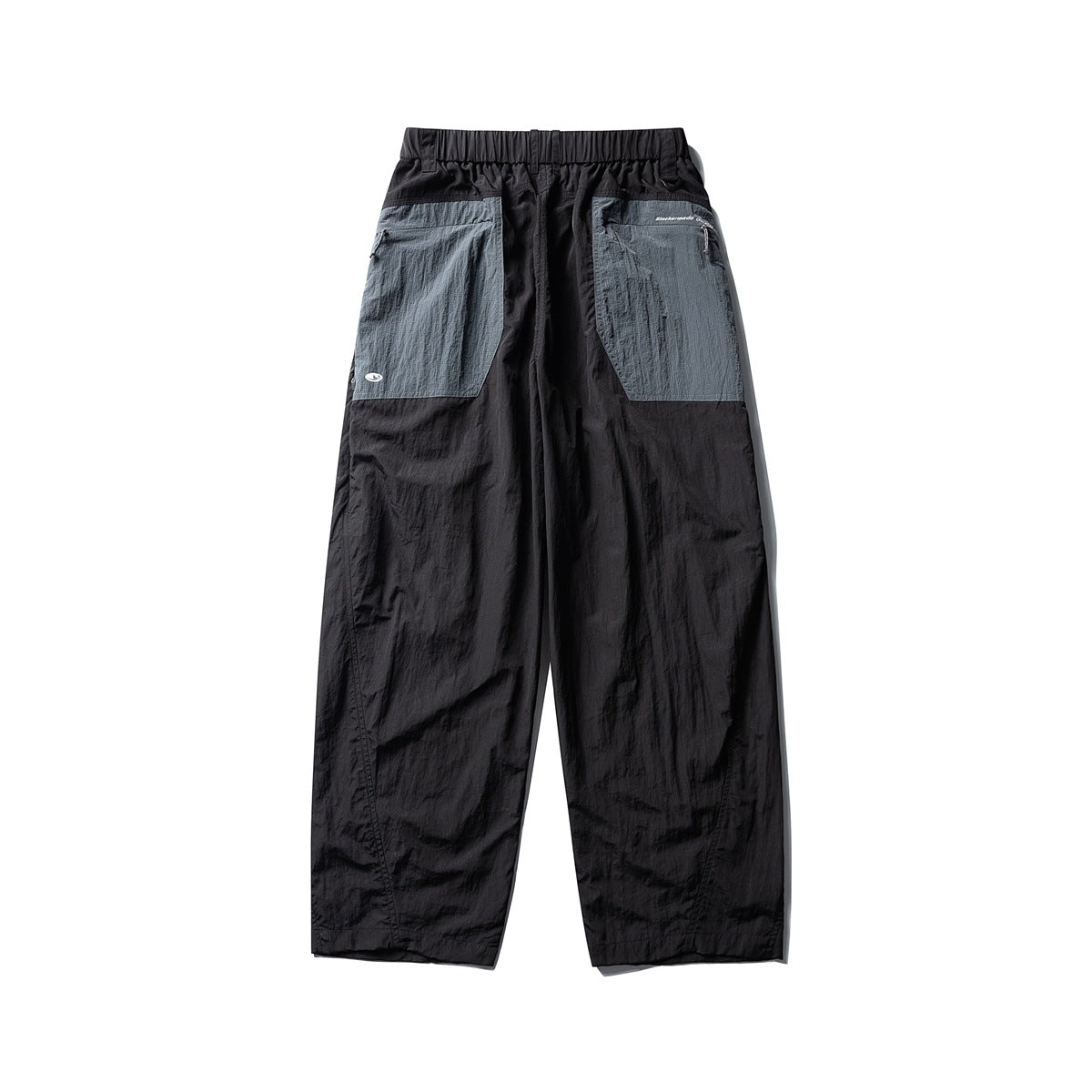 Rear view of loose black pants with a gathered waistband and two large gray patch pockets.