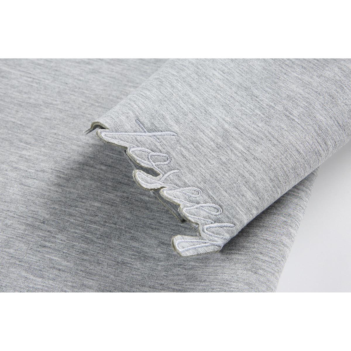 Close-up of a heather-gray sleeve edge with raised white embroidery.