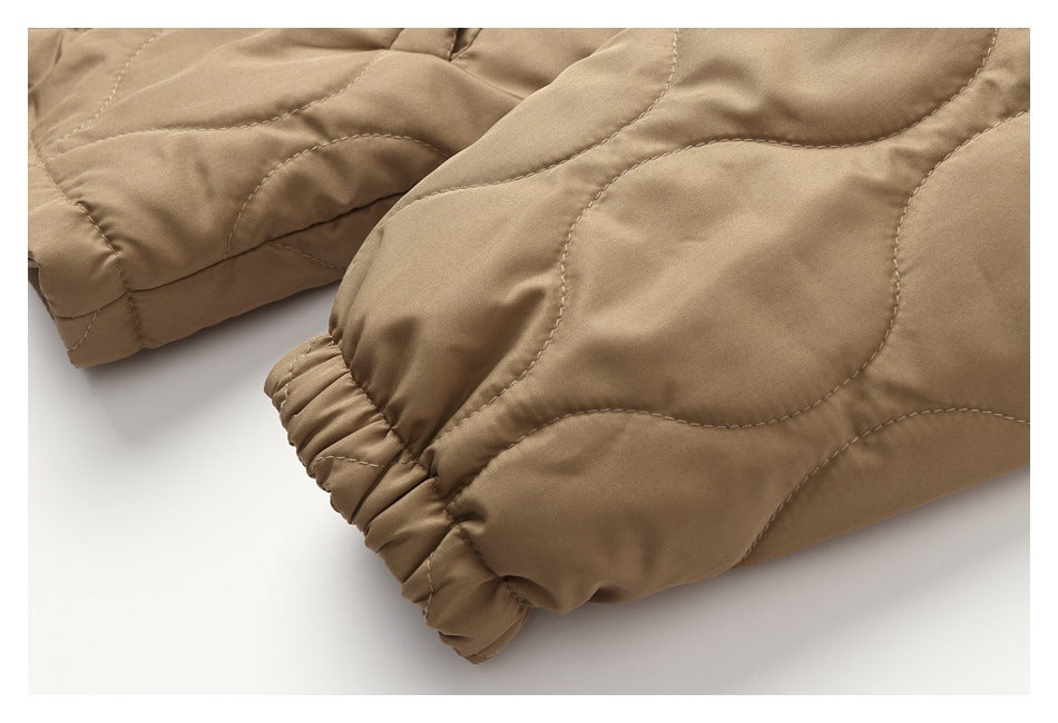 Close-up of a tan jacket sleeve with curved quilting and an elasticated cuff.