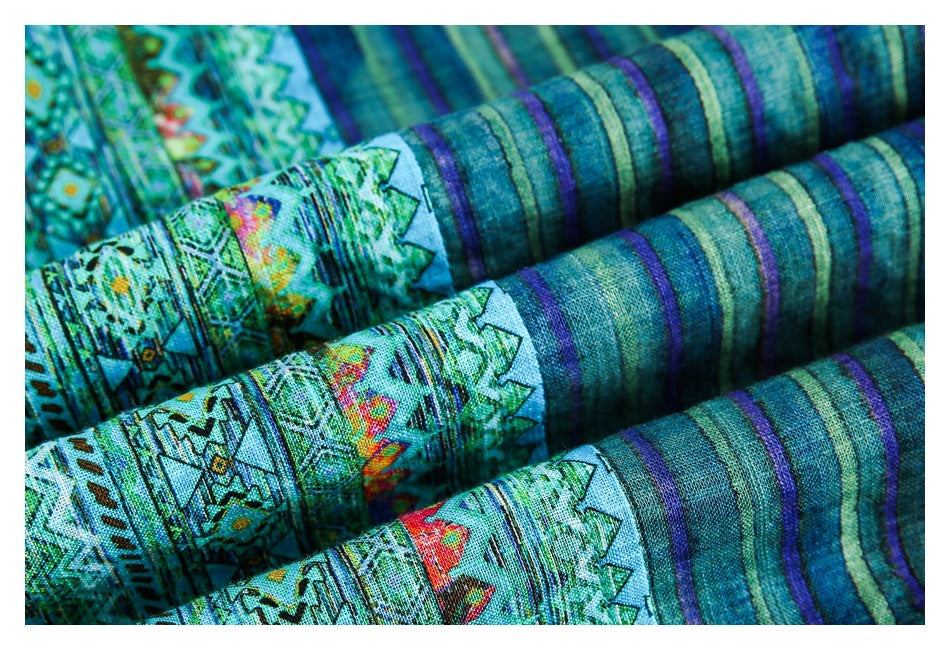 Close-up of folded turquoise geometric-print fabric with alternating teal and purple stripes.