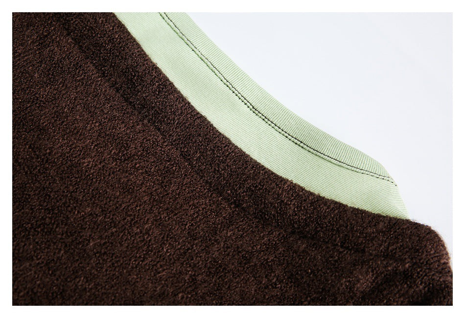 Close-up of the pale green neckline and shoulder edge against dark brown fuzzy fabric.