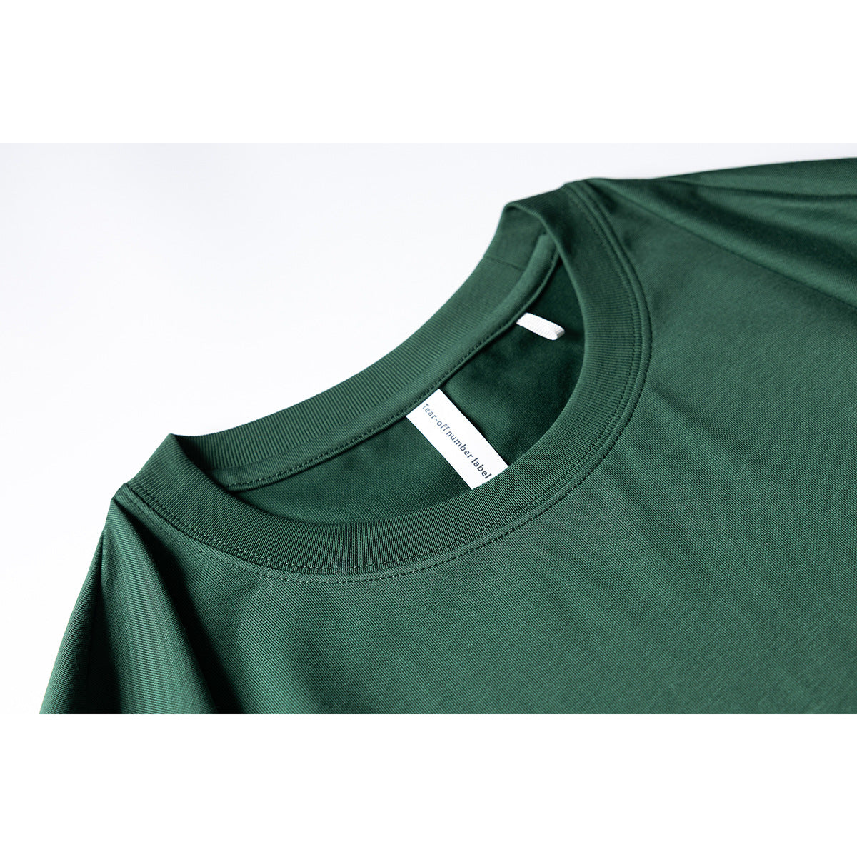 Close-up of a dark green T-shirt’s ribbed crew neck, stitching and inner label.