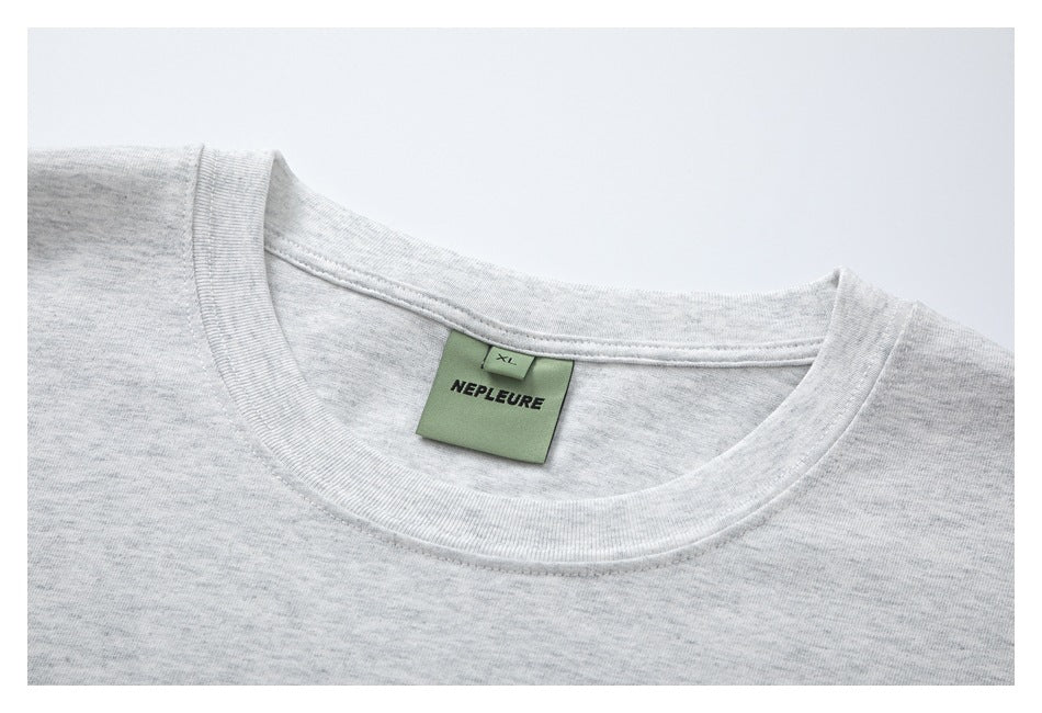 Close-up of a light heather gray T-shirt neckline and green NEPLEURE label marked XL.