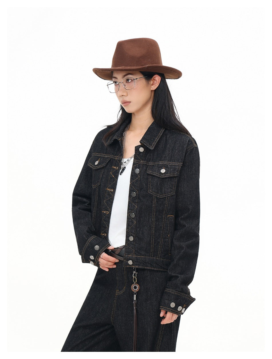 Three-quarter front view of a model wearing a black denim jacket with contrast stitching and metal buttons.