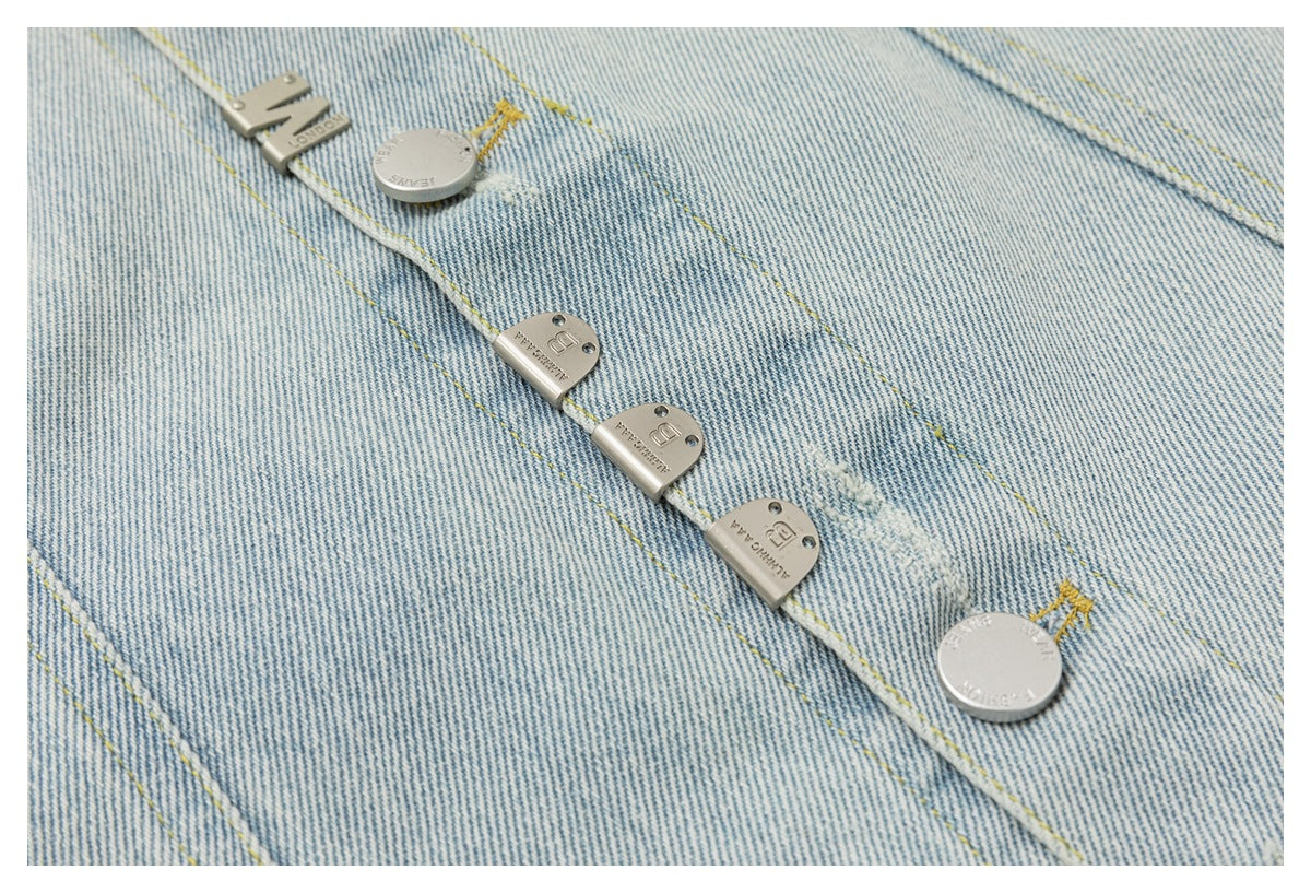 Close-up of a pale blue denim jacket placket with silver-tone fasteners and yellow stitching.
