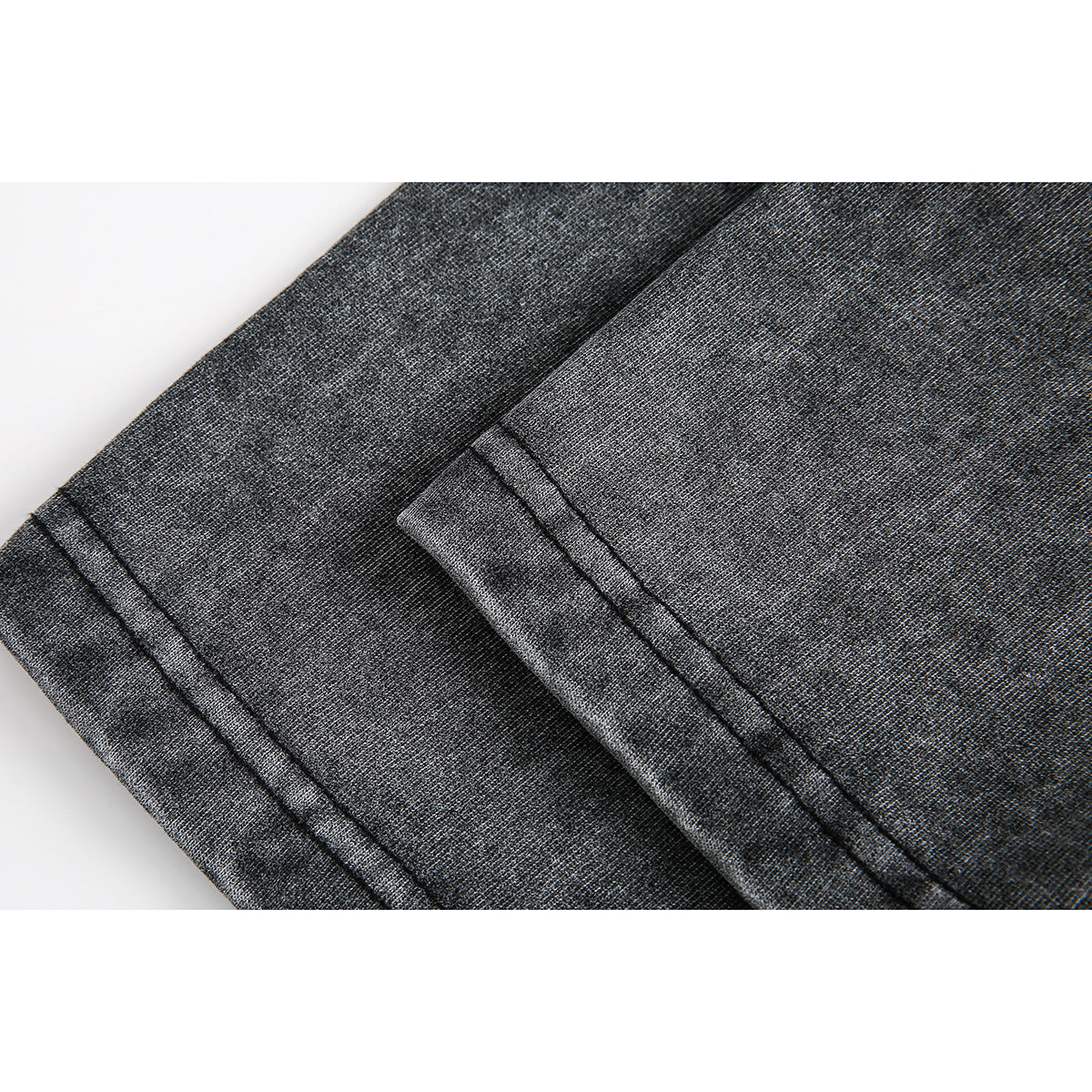 Close-up of dark charcoal garment fabric with a folded edge and parallel stitching.