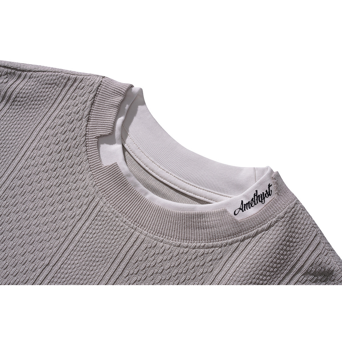 Close-up of a light gray textured crewneck top with a ribbed neckline and a white inner layer.