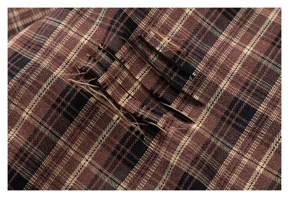 Close-up of a brown plaid shirt seam with loose threads and a narrow stitched opening.