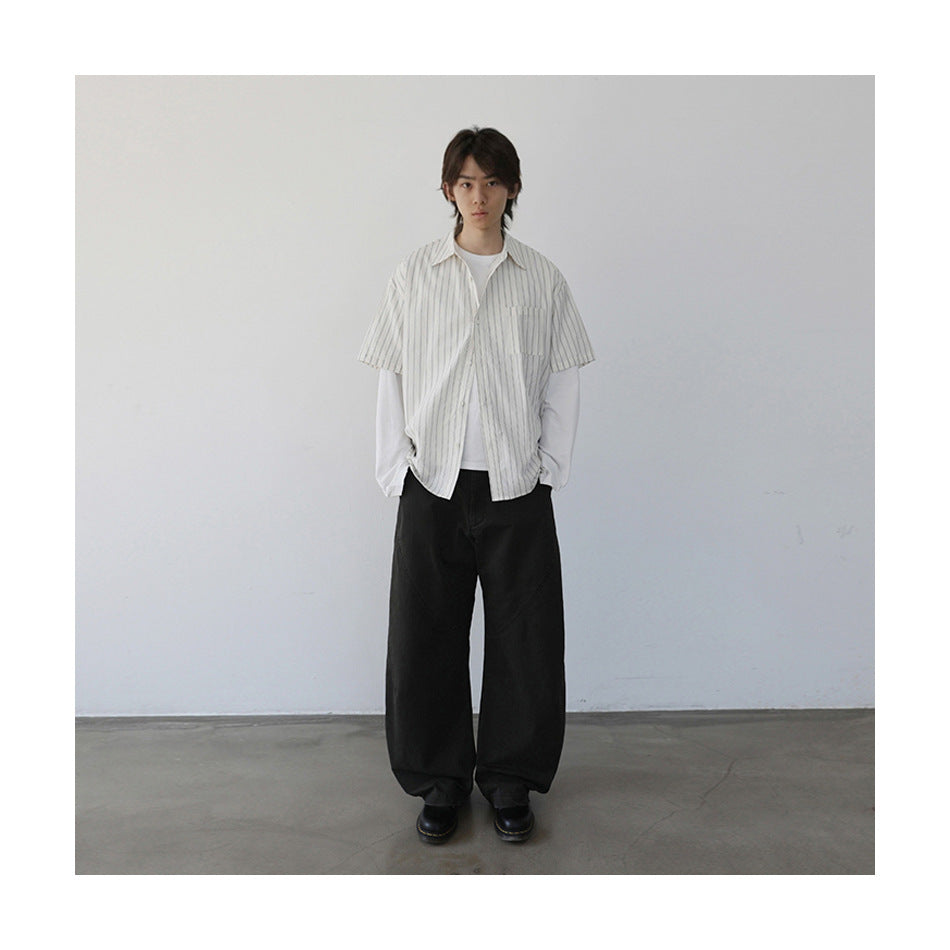 Model in striped short-sleeve shirt over a white long-sleeve tee with wide black pants and black boots