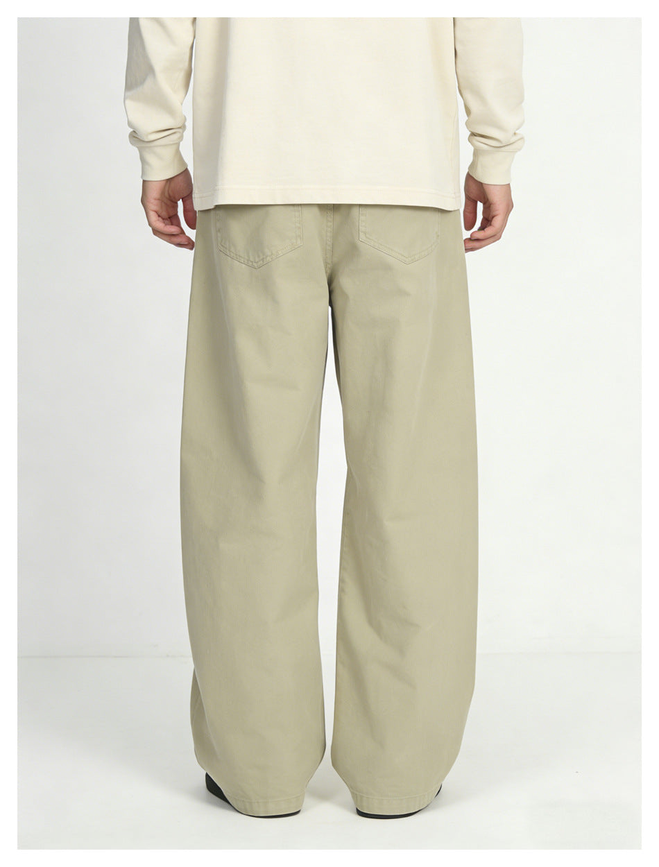 Rear view of a model wearing loose light khaki wide-leg pants with back pockets and a cream long-sleeve shirt.