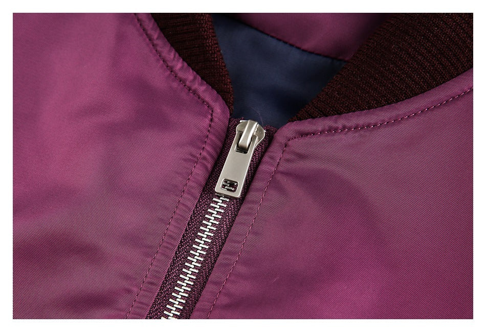 Close-up of the silver zipper and stitching on a plum bomber jacket.