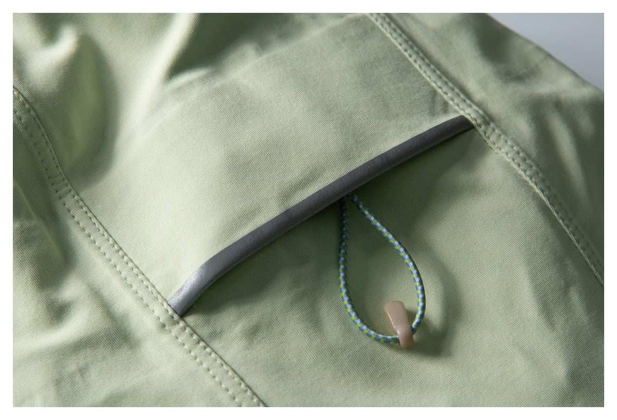 Close-up of a pale green garment pocket with a cord loop and reflective trim.