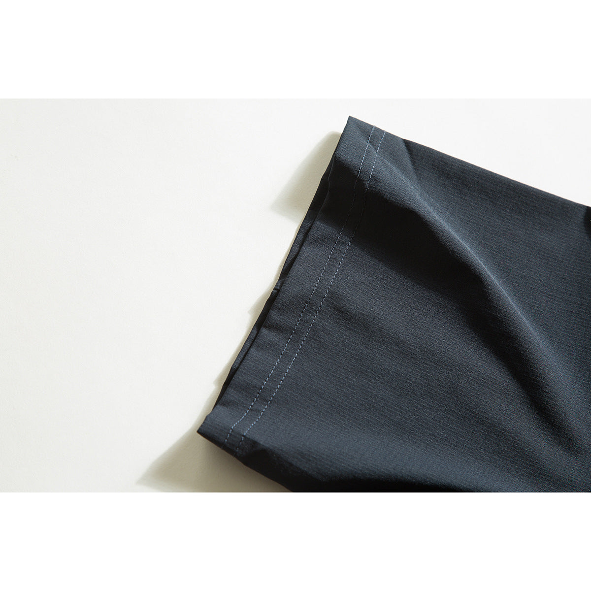Close-up of a dark shirt sleeve edge with parallel rows of stitching.