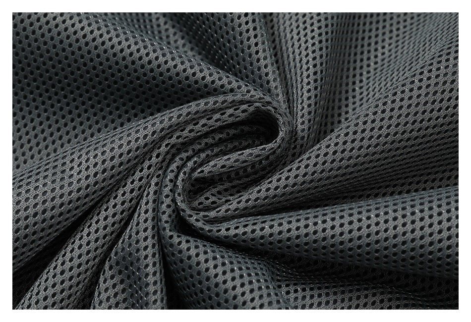 Close-up of gray-black mesh fabric with evenly spaced small oval openings, gathered into folds.