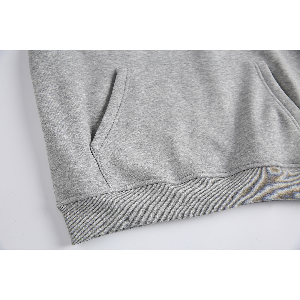Close-up of a heather-gray hoodie showing its kangaroo pocket and ribbed hem.