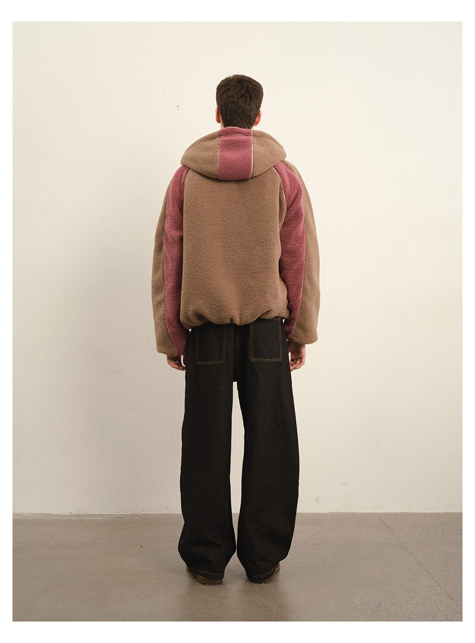 Rear view of a model wearing a brown and dusty pink color-block hooded jacket with black trousers.