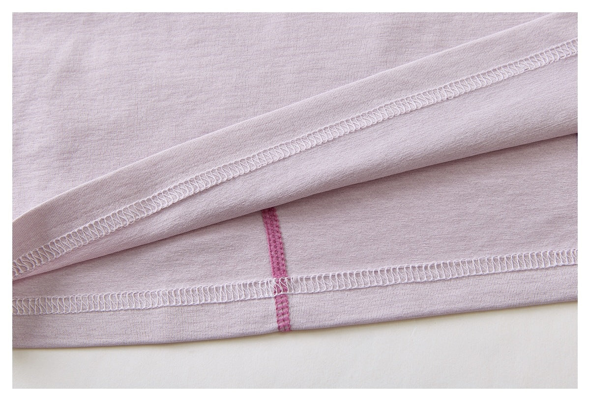 Close-up of the pale lavender top’s folded hem and overlocked stitching, with a pink seam visible beneath.