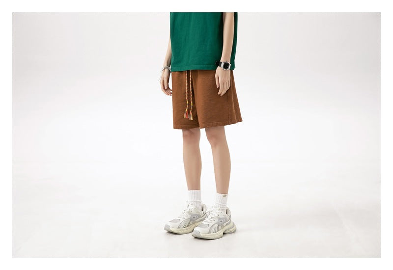 Model wearing brown drawstring shorts with a green T-shirt, shown from a slight front angle.