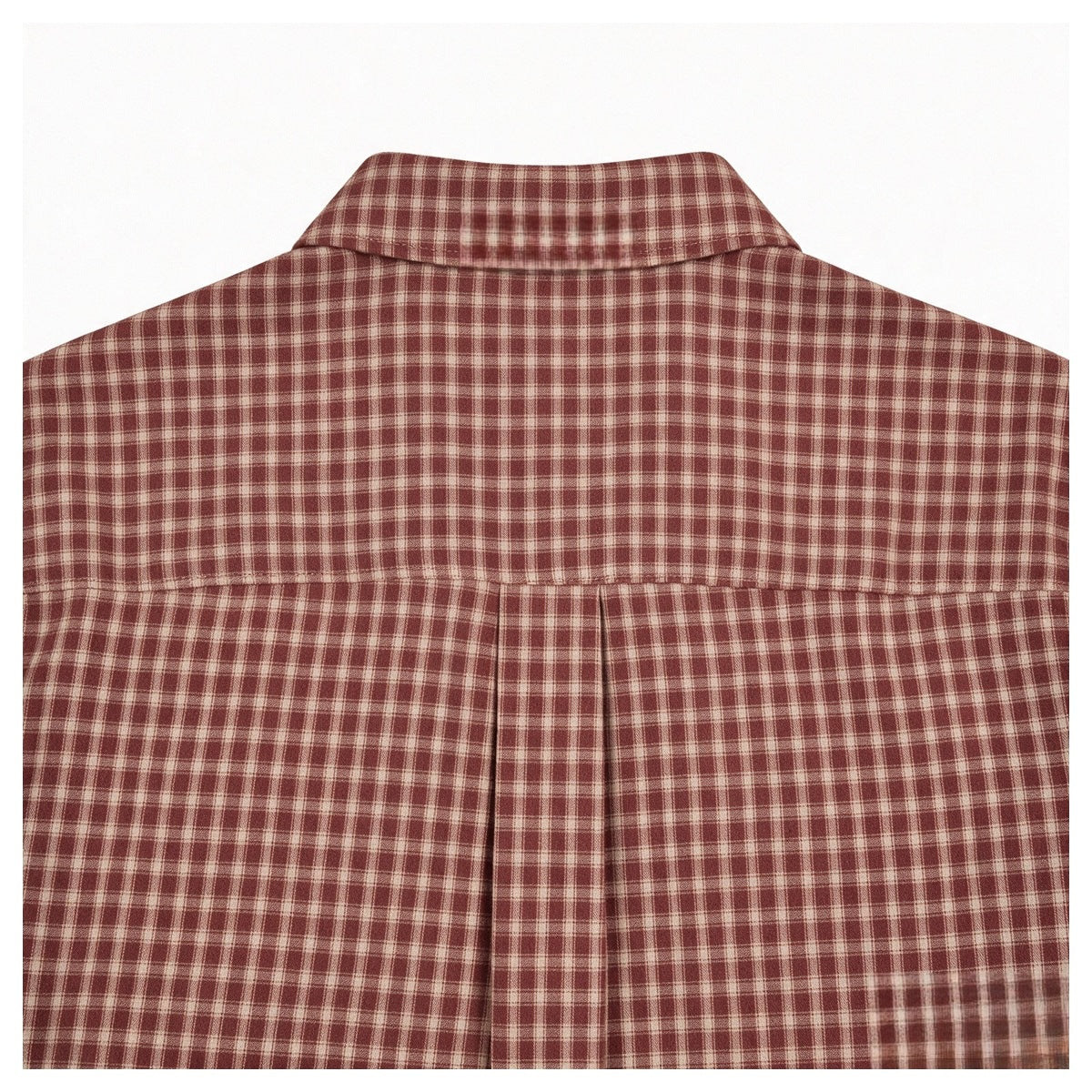 Close-up of the back yoke and collar of a rust-red and cream plaid shirt.