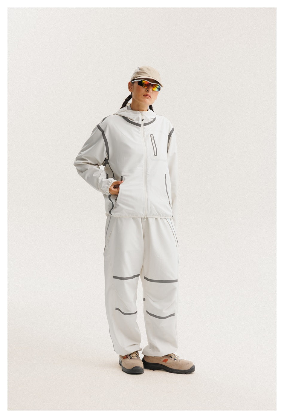 Model wears a white hooded zip jacket with gray accents and relaxed matching pants.