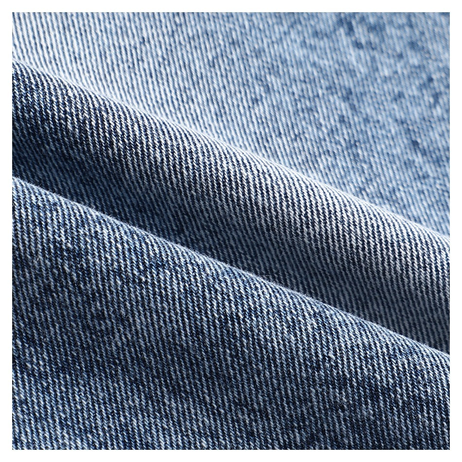 Macro view of blue denim fabric folded to show its diagonal weave and texture.