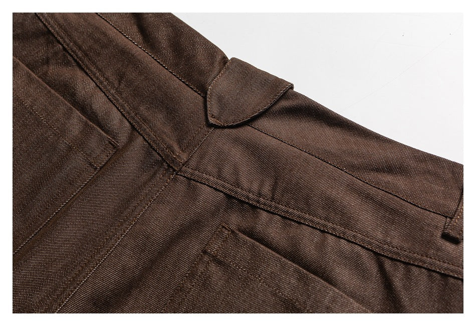 Close-up of dark brown trousers showing the waistband, belt loop, seams, and pocket edge.