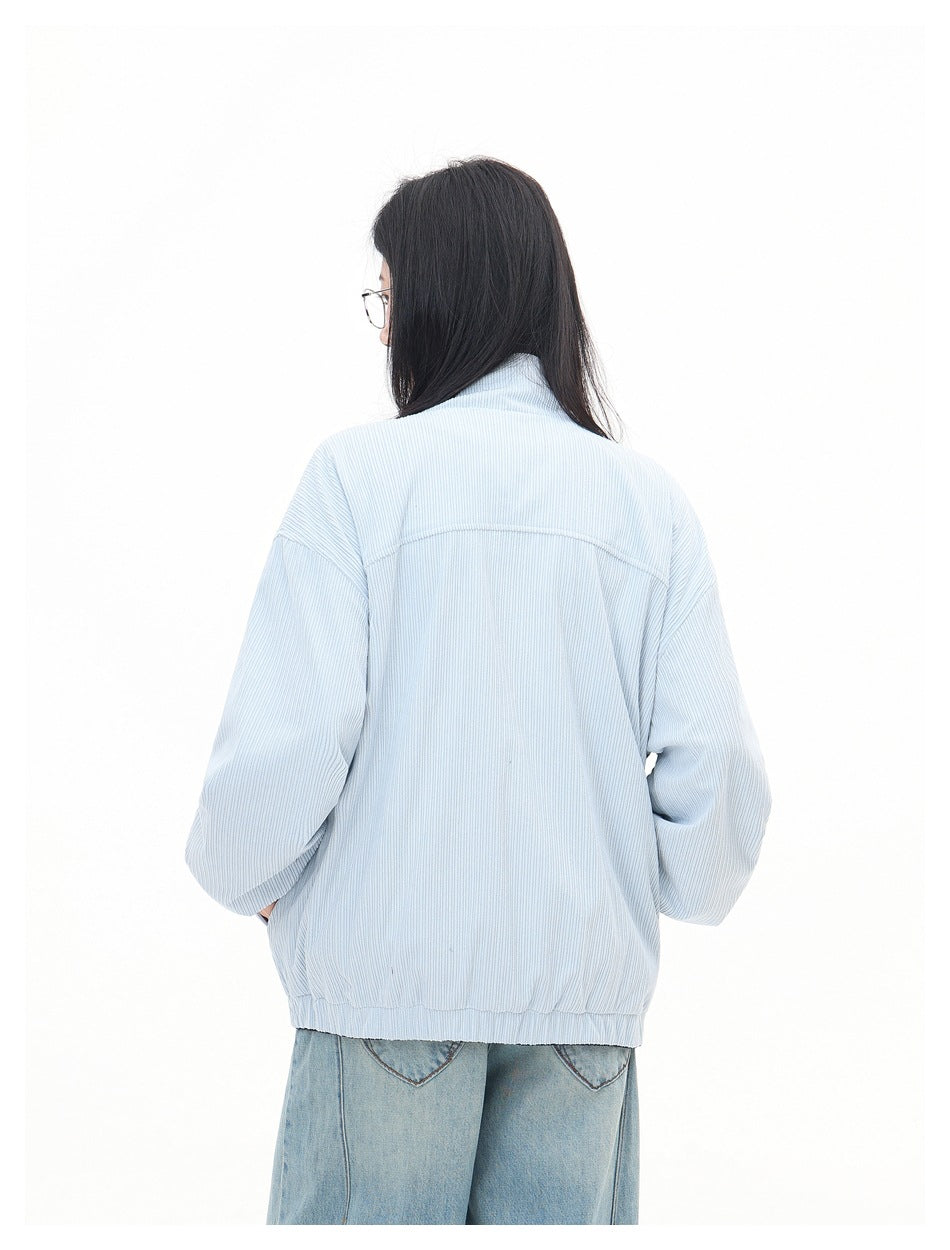 Back view of a model wearing a pale blue ribbed jacket with a gathered hem and dropped shoulders.