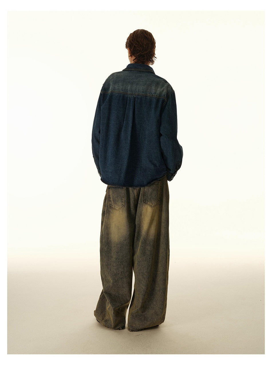 Back view of a model wearing a dark indigo denim shirt with a lighter faded yoke and wide jeans.