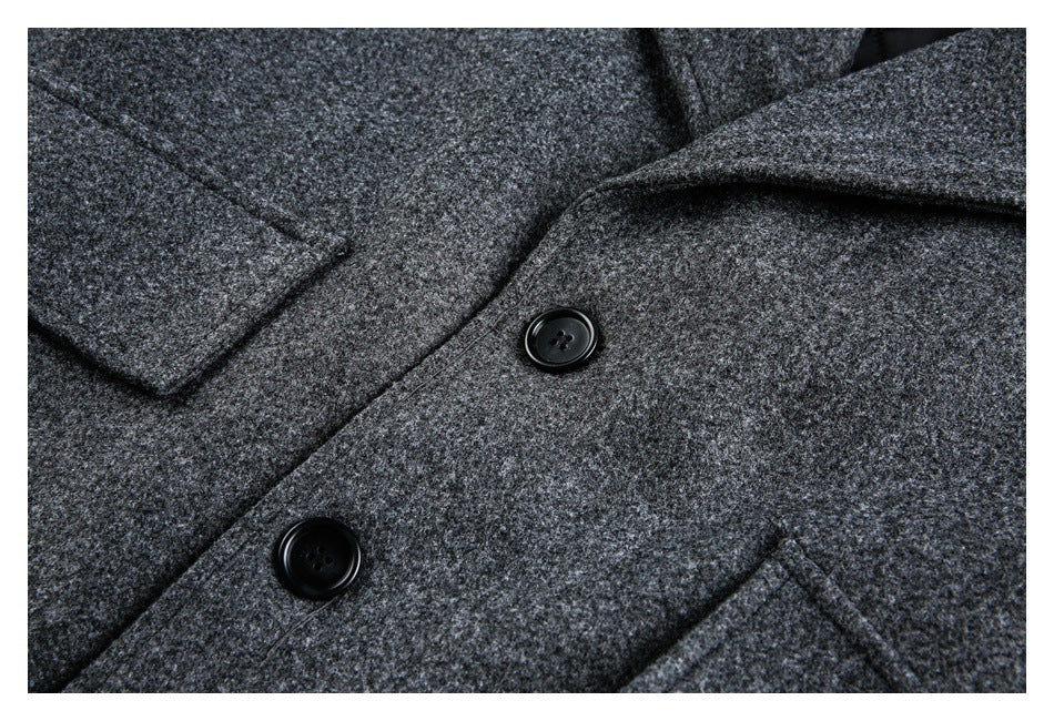 Close-up of a charcoal coat's textured surface, wide lapel, black buttons, and front pocket edge.