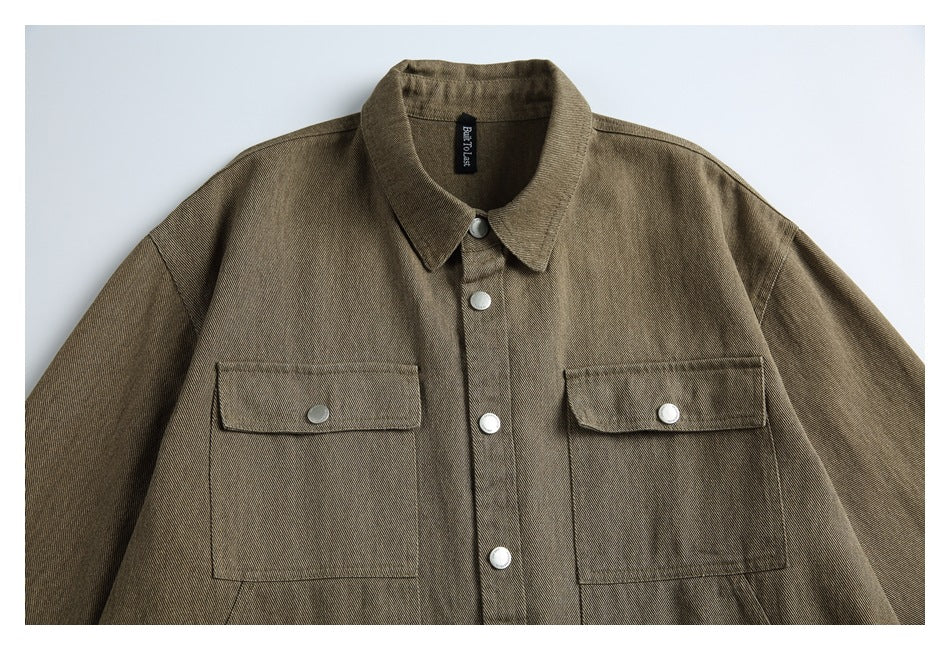 Front view of a brown-olive shirt jacket with a pointed collar, silver buttons, and two large flap chest pockets.