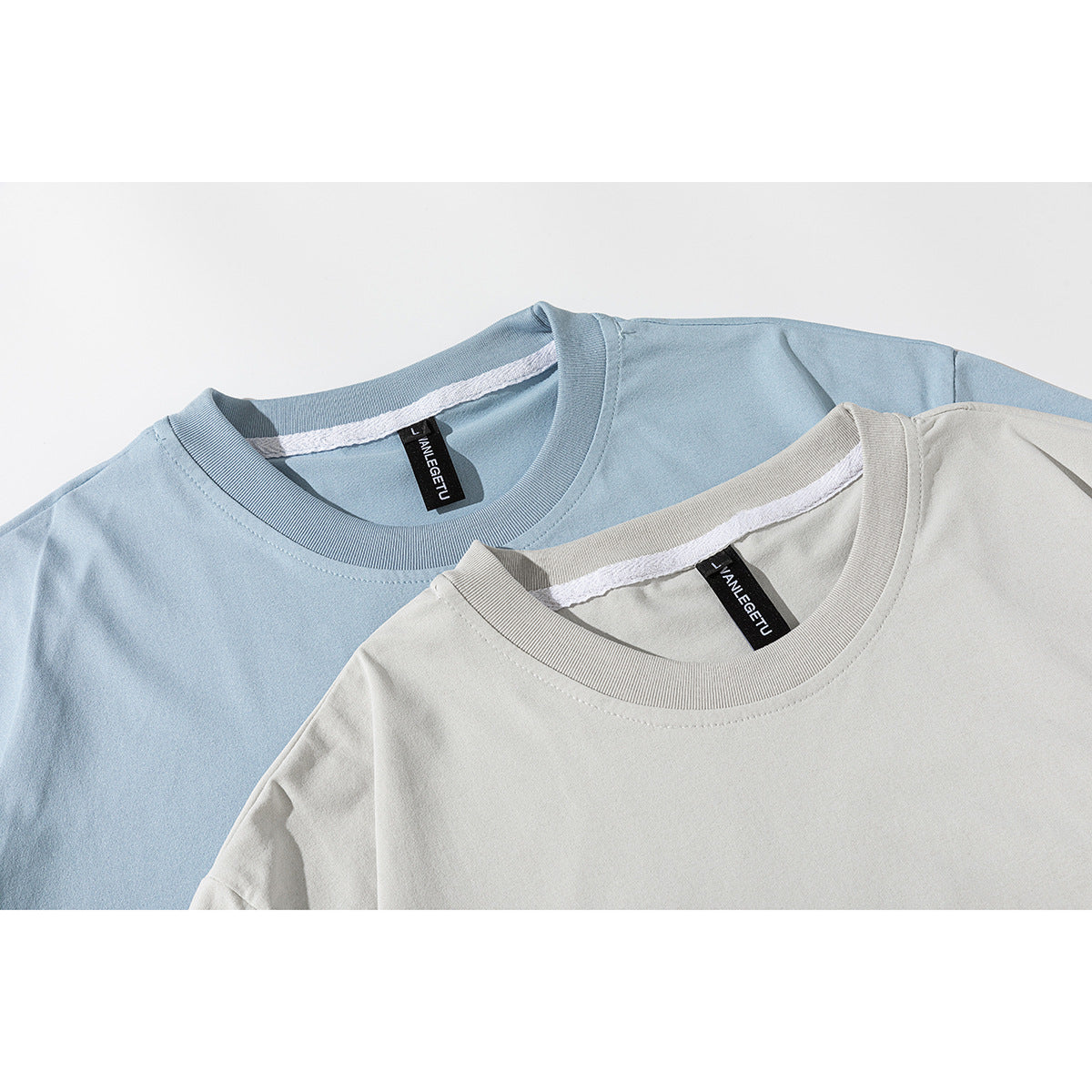 Close-up of blue and light gray T-shirts showing ribbed crew necks and inner neck labels.