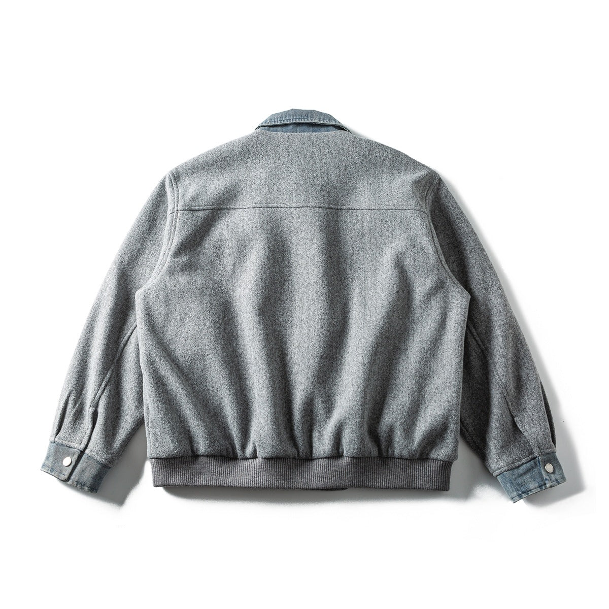 Back view of a light gray jacket with a blue denim collar and cuffs and a ribbed hem.