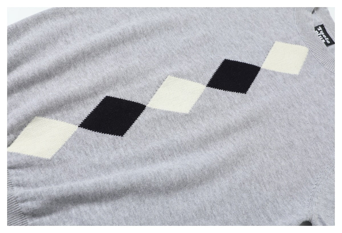 Close-up of a light gray sweater showing a diagonal row of cream and black diamond motifs across the front.